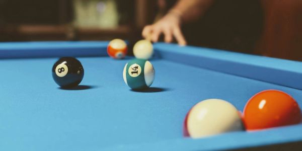 Pool balls on a blue table as someone prepares to strike.