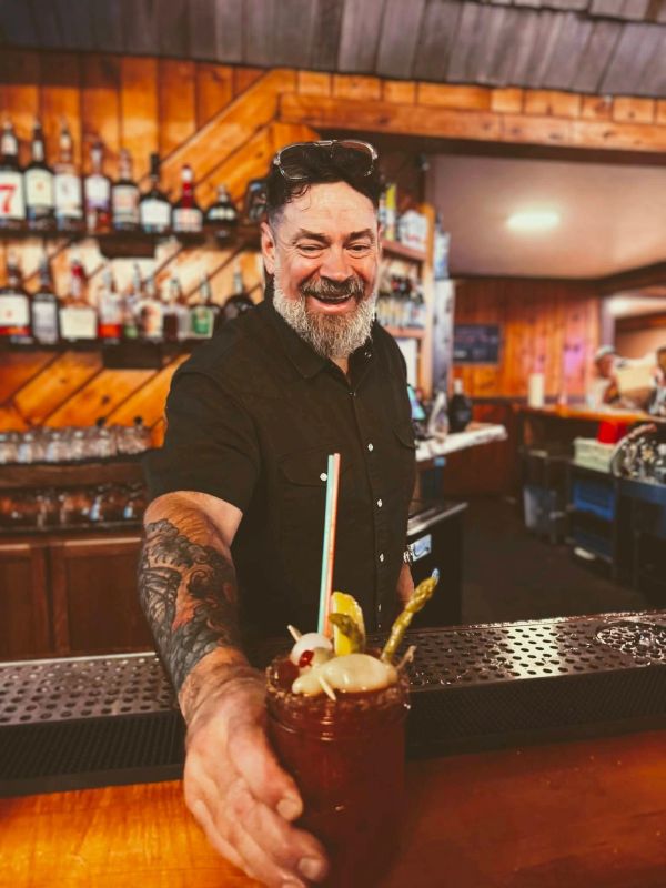 Smiling bartender serving a drink at the bar.