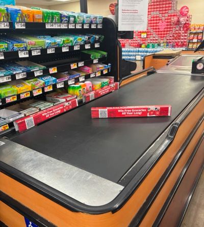 A grocery checkout conveyor belt with gum and mints for sale.
