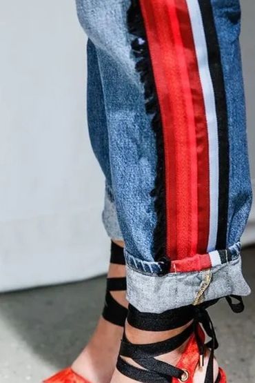 Denim jeans with red, white, and black side stripes and rolled cuffs.