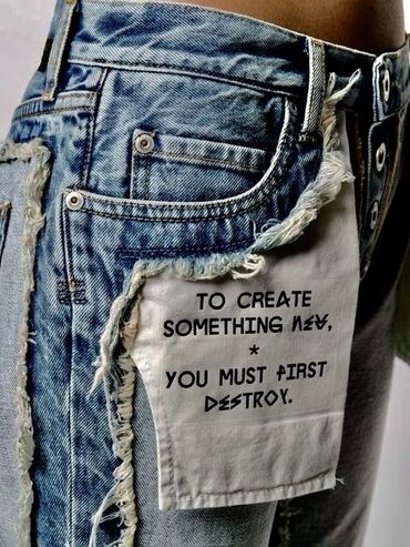 Denim jeans with a patch reading, 'To create something new, you must first destroy.'