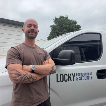Man with tattoos standing confidently by locksmith van.