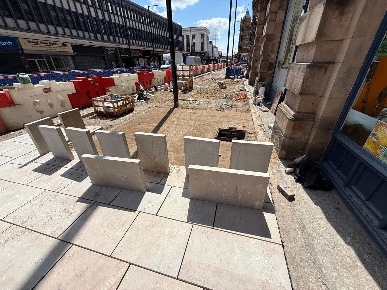 Construction site with stone slabs and barriers on a city street.