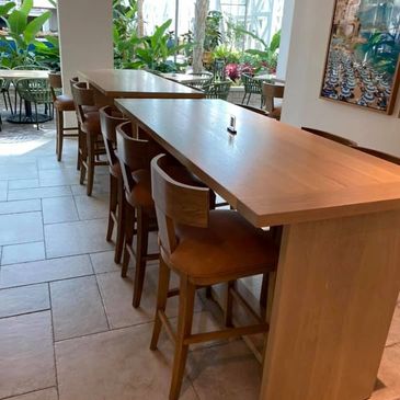 Outdoor table with brown chairs and a beach image hanging on the wall