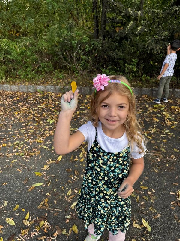 Children holding leaves and exploring nature outdoors
