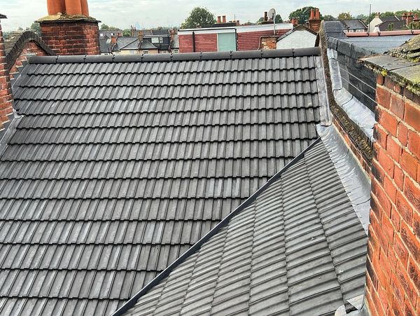 View of a tiled roof and red brick chimneys in a residential area.