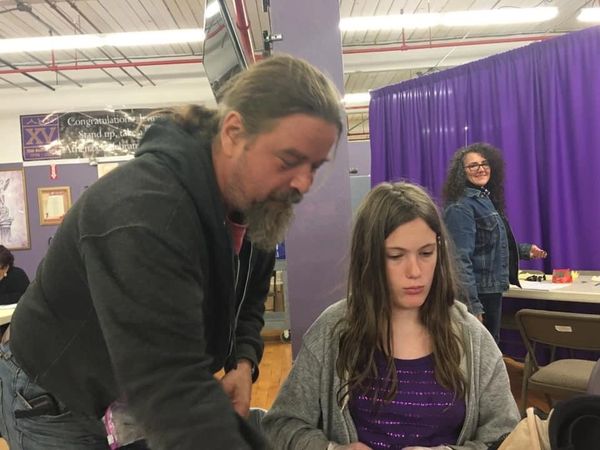 A girl being taught how to clamp bra hooks together