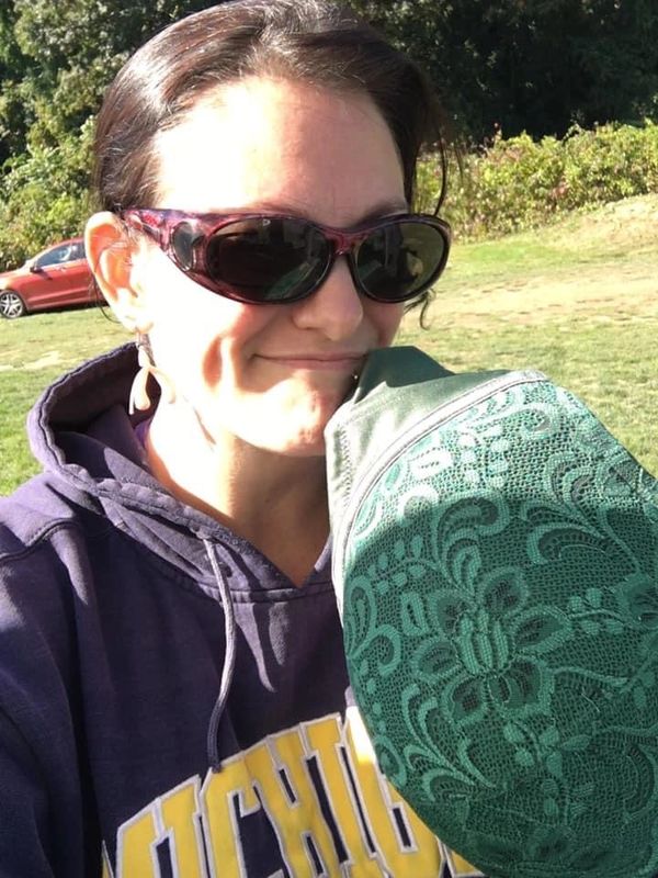 Goddess Jenn holding her favorite green bra for donation to the chain