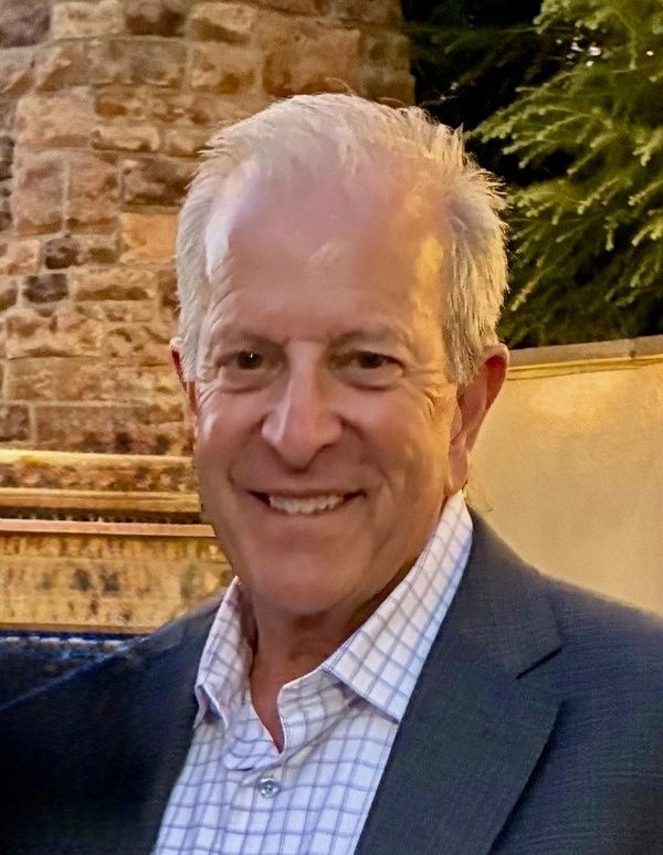Smiling elderly man in a suit jacket.