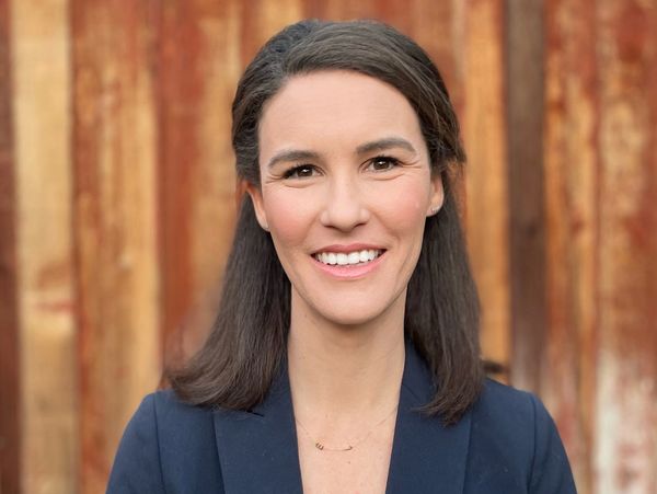 Smiling woman with dark hair in blue blazer.