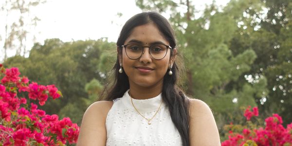 Young woman smiling outdoors with flowers.