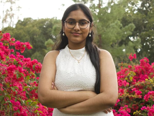 Young woman smiling outdoors with flowers.