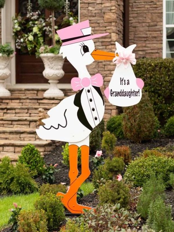 Pink stork yard sign holding a baby announcement.
