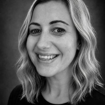 Black and white portrait of a smiling woman with wavy hair.