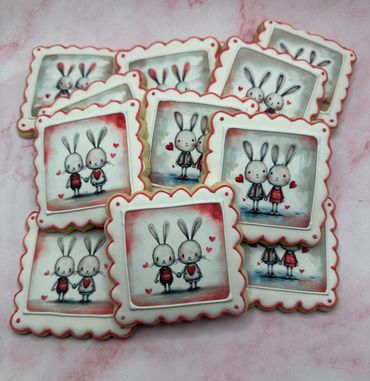 Square cookies decorated with cute bunny couples holding hands and surrounded by hearts.