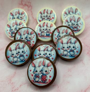 Round chocolates with cute bunny couple illustrations in white and milk chocolate.