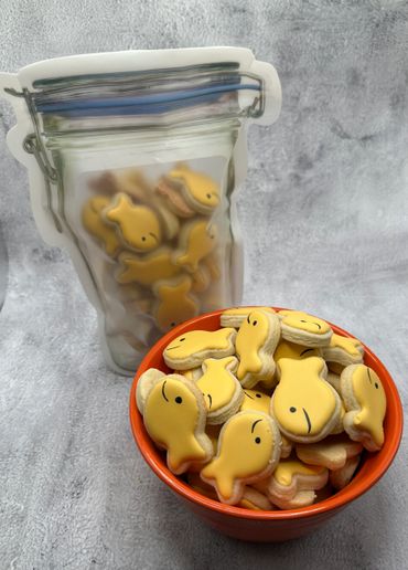 Yellow fish-shaped cookies in an orange bowl and a resealable bag.