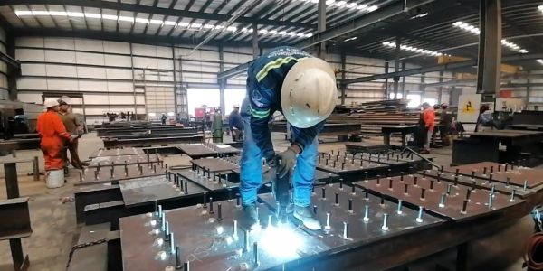 Worker welding metal in a large industrial workshop.