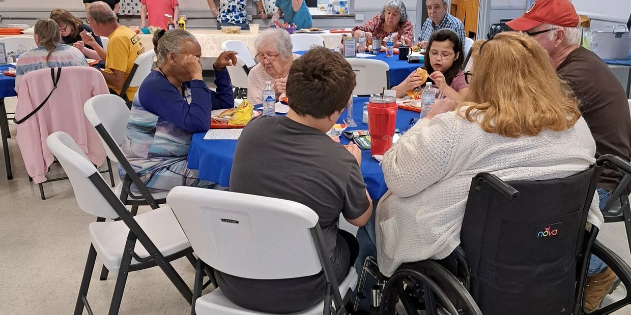 Community members of all ages sharing a meal in a bright, welcoming hall.