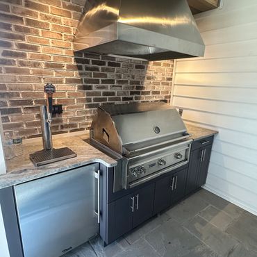 Modern outdoor kitchen with stainless steel grill and beer tap.