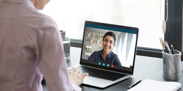 Person video chatting with a smiling woman on a laptop.