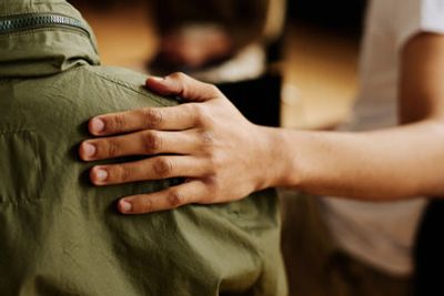 A hand gently resting on someone's shoulder, showing support.