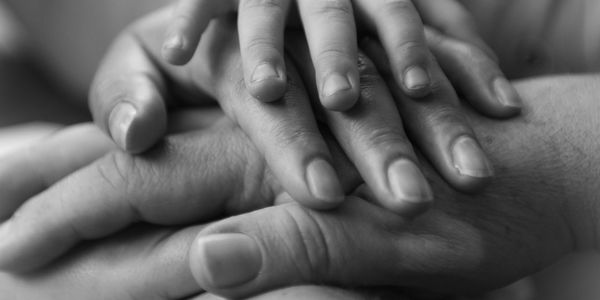 Close-up of hands gently touching in black and white.