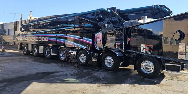 Large black concrete pump truck with colorful stripes.