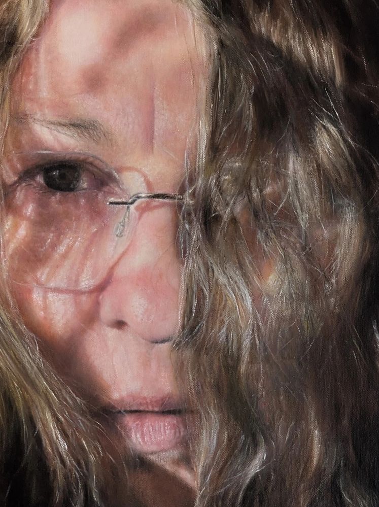 Hyper-realistic painting of a woman's face with long hair on an easel, surrounded by art supplies.