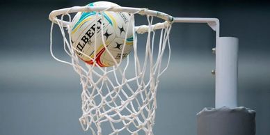 Netball ball passing through the hoop net during game.