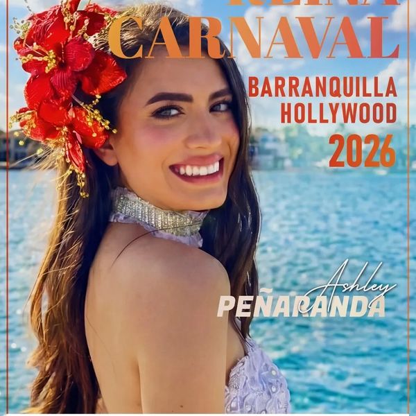 Young woman with a red floral headpiece smiles by the water.