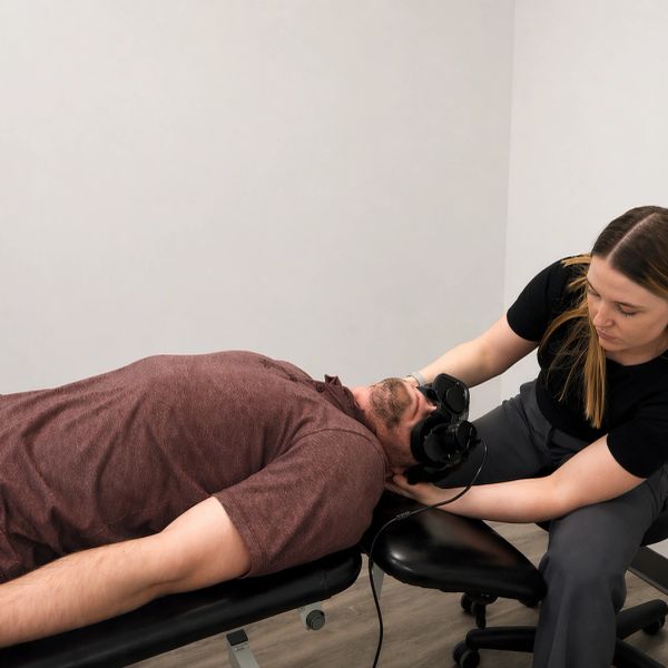 Therapist performing neck treatment on a patient lying on a table.