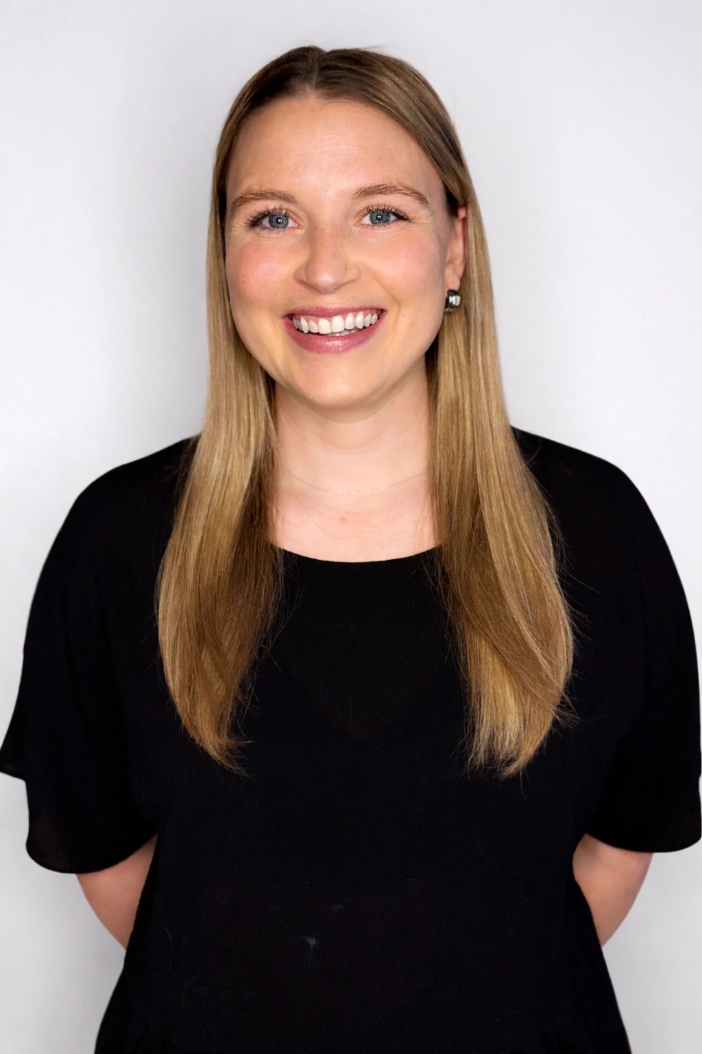 Smiling woman with long blonde hair in a black top against a white background.
