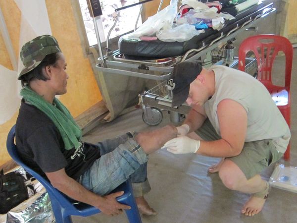 Zak is inspecting amputation of local villager who previously stepped on land mine.