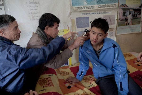 Showing local medical staff how to use otoscope on patient with perforated eardrum.