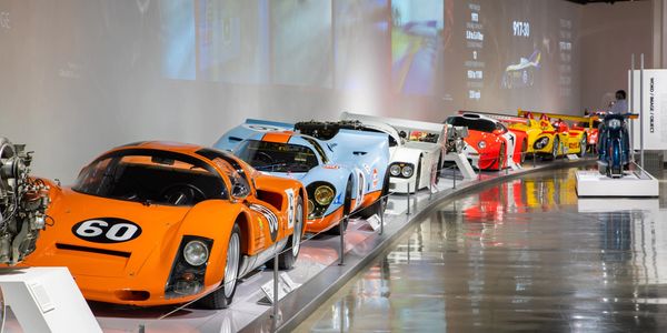 A lineup of colorful vintage race cars displayed in a museum.