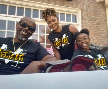 Happy family smiling together outdoors in front of a windowed wall.