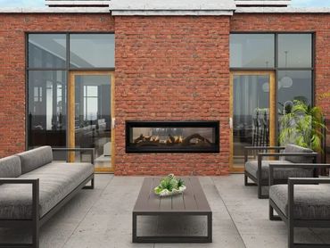 Modern outdoor seating area with a brick fireplace and gray cushioned furniture.