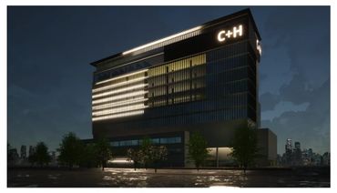 Modern office building illuminated at night with C+H logo.