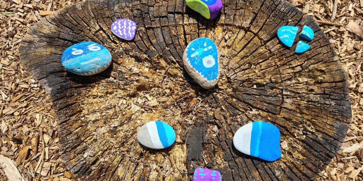 Painted rocks arranged on a tree stump.