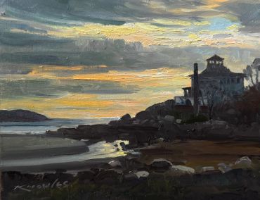 Sunset over rocky shoreline with silhouetted house.