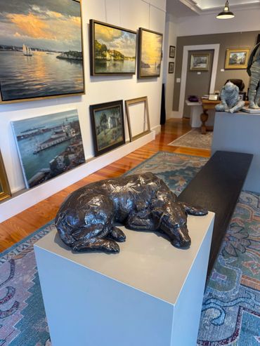 Art gallery with sculptures and landscape paintings.