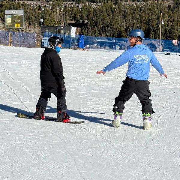 Two people in helmets skiing or snowboarding on a snowy slope.