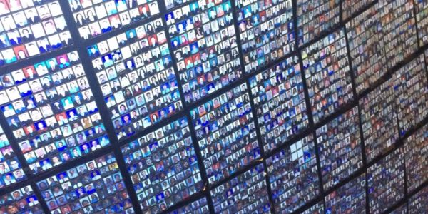 Wall covered with numerous small digital photos arranged in grid.