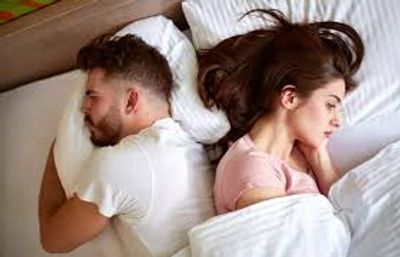 A couple experiencing sexual problems, they are in bed, but have turned away from each other.