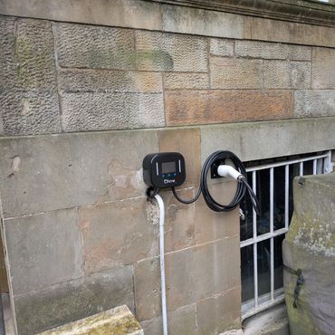 Electric vehicle charging station on stone wall.