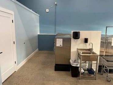 Laundry room corner with washer, sink, and cart.