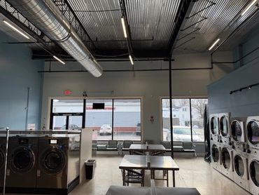 Modern laundromat with washers, dryers, and seating area.
