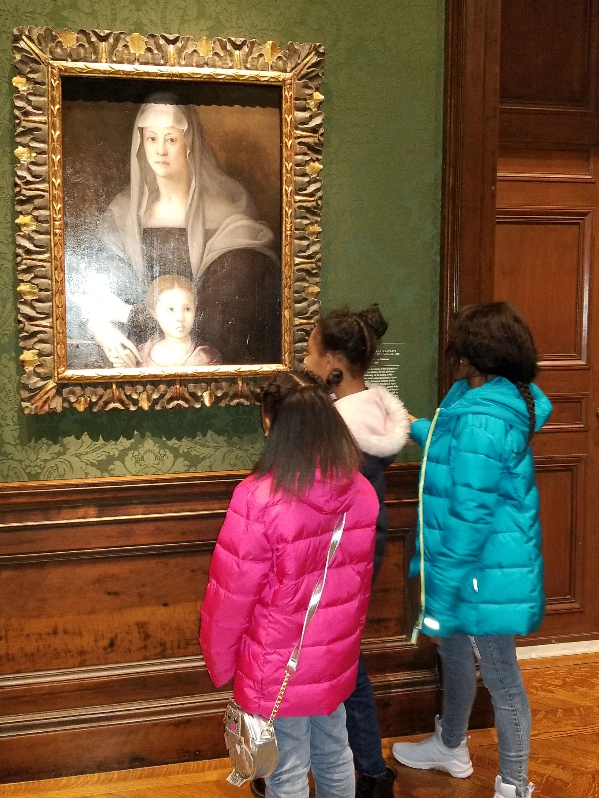 Three girls standing and looking at painting