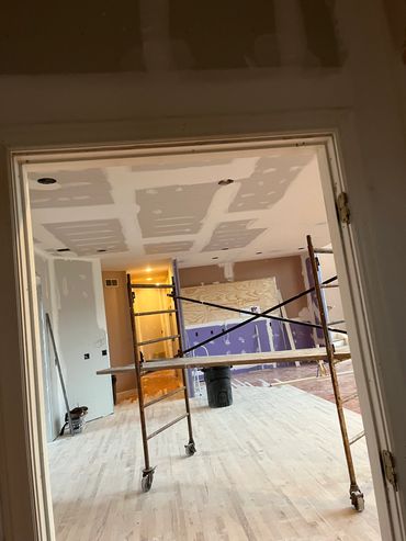 Room under construction with scaffolding and drywall work.
